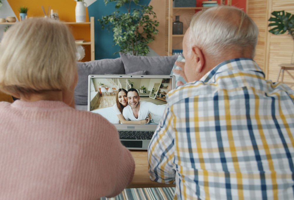 Un couple de seniors en appel vidéo avec ses enfants sur un ordinateur