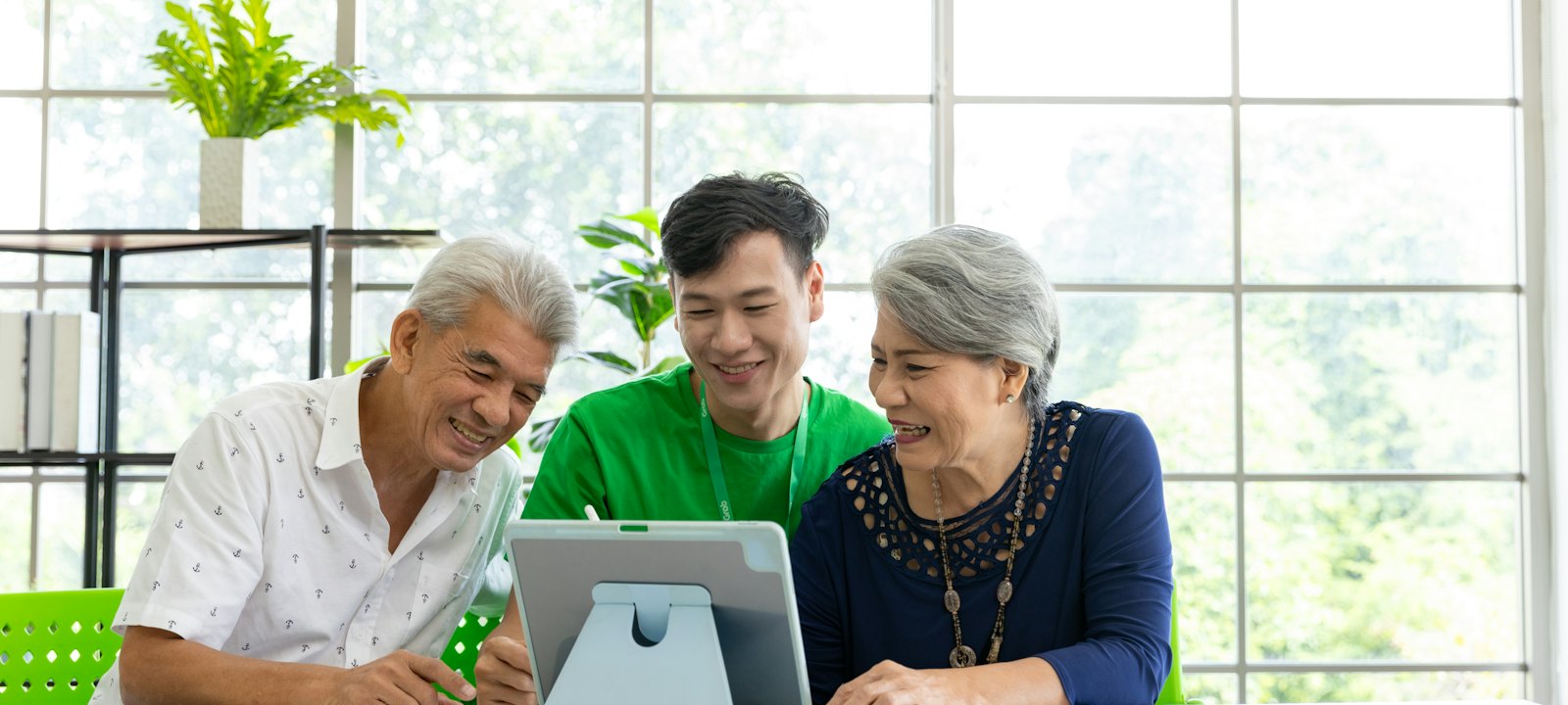 Un formateur montre une tablette à un couple de seniors, qui rient